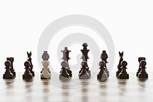 Single white pawn in initial line up of black chess pieces