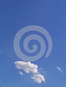 single white soft cloud on a bright clear sunny blue sky