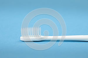 Single white toothbrush close up isolated on blue background horizontal