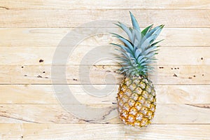 Single whole pineapple with green leaves on the wooden texture background