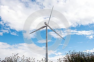 Single wind turbine against a cloudy blue sky