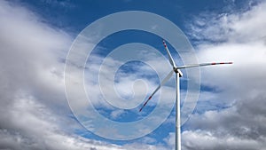 Single wind turbine against a heavily cloudy blue sky.