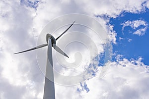 Single Wind Turbine under blue sky with clouds. Windfarm, wind power plant