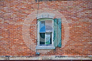 Old brick wall with single window and green shutter
