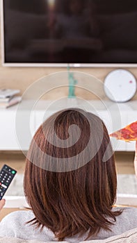 Single woman eating pizza and watching tv