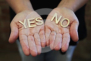 A single woman with her hands together with wooden letters forming the words Yes and No