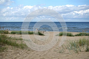 Single woman sits on the bench on sandy beach in low season and looking to sea skyline