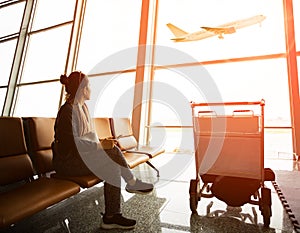 Single woman sitting in airport terminal and passanger plane fly