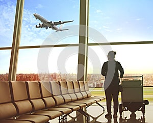 Single woman sitting in airport terminal and passenger plane fly