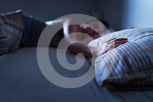 Single woman sleeping alone in bed at home. Lonely lady missing husband or boyfriend. Hand on pillow.