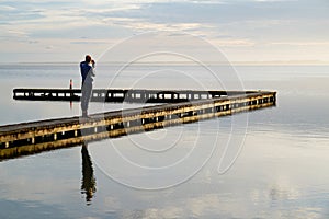 Single woman standing on wooden pier pontoon access boat in Biscarrosse lake sunrise photo