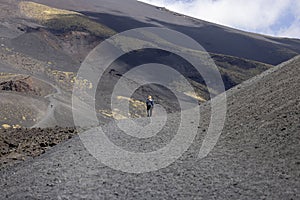 Single woman walking path on Crater Silvestri on the slope of volcano Mount Etna, Sicily, Italy