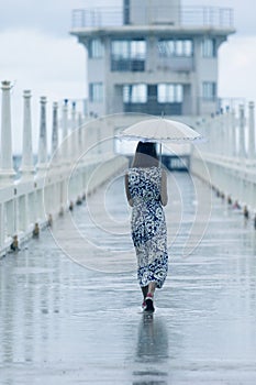 Single woman walking on way with umbrella and rain dropping