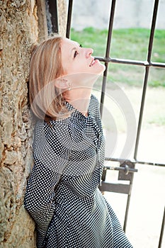 Single women, outdoors, next to the metal wall with hopeful expression.