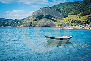 Single wooden row boat moored in calm waters of the bay on a summer day