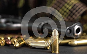 Single yellow brass bullet detail, black metal gun in background