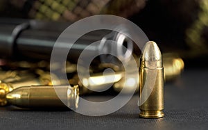 Single yellow brass bullet detail, black metal gun in background