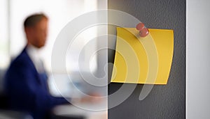 Single yellow post-it note attached to wall with push pin