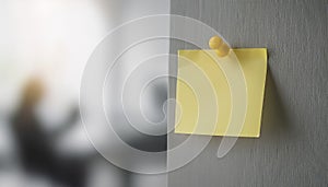 Single yellow post-it note attached to wall with push pin