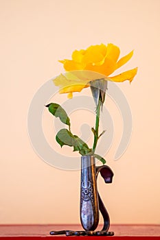 Single yellow rose in a tiny silver ornate vase in a yellow room