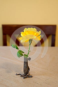 Single yellow rose in a tiny silver ornate vase in a yellow room