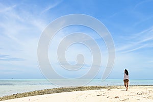 Single young Asian girl walking on tropical white sand beach photo