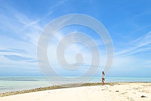 Single young Asian girl walking on tropical white sand beach photo