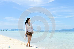 single young Asian girl walking on tropical white sand beach, photo