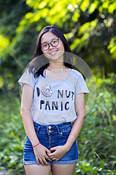 Single young trendy energetic Asian lady with long hair spectacles wearing short denim jean at park.