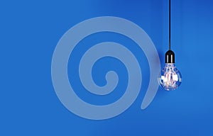 Singular hanging light bulb on bright blue background with space for text. 3d rendering