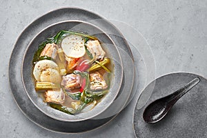 Sinigang na Baboy dish or Filipino Pork Meat Soup in gray bowl on concrete backdrop. Filipino Food. Asian Meal photo
