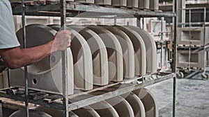 Sink blanks are stacked on a rack-cart in a plumbing production facility. Stage of production of ceramic sanitary ware