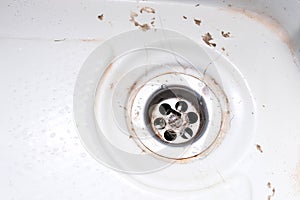 A sink drain hole with limescale or lime scale and rust on it, dirty rusty bathroom washbowl