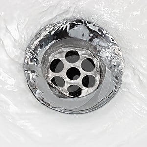 Sink plug drain hole bath plughole, white basin spout, running water macro closeup, stainless steel, china porcelain hand