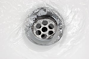 Sink plug drain hole bath plughole, white basin spout, running water macro closeup, stainless steel, china porcelain hand