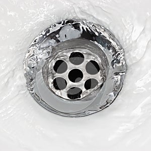 Sink plug drain hole bath plughole, white basin spout, running water macro closeup, stainless steel, china porcelain hand