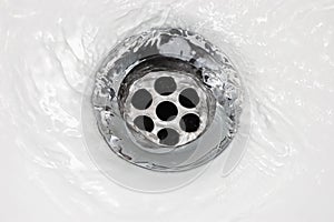 Sink plug drain hole bath plughole, white basin spout, running water macro closeup, stainless steel, china porcelain hand