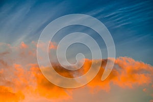 Sinlit orange clouds in blue sky at sunset