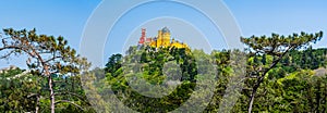 Panoramic skyline view of the National Palace of Pena and Castle of the Moors on the hill top surrounded by a green forest in