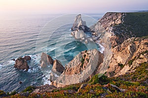 Sintra, Portugal. Praia da Ursa or Ursa Beach impressive unique sea stacks and cliffs in evening sunset light on