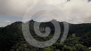 Sintra\'s Natural Park with distant hilltop Pena Palace against cloudy sky