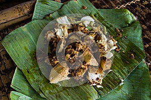 Siomay - Indonesian dish with steamed fish dumpling and vegetables served in peanut sauce in banana leaf in close-up