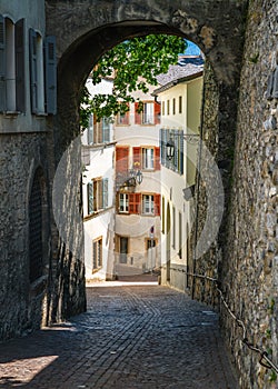 Sion old town vertical view with scenic pedestrian laneway with paved street and medieval arch and buildings in Sion Switzerland photo
