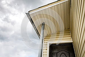 SIP panel house construction. Brown rain gutters. Drainage system with plastic siding and eaves on blue sky background