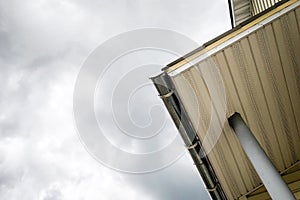 SIP panel house construction. Brown rain gutters. Drainage system with plastic siding and eaves on blue sky background