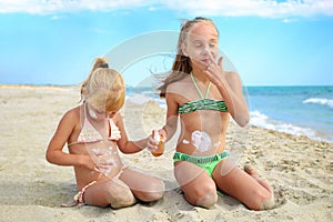 Sister applying protective sunscreen on young child. Girl draws sun cream