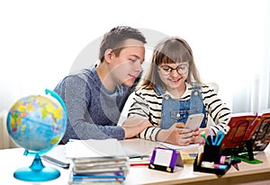 Sister and brother do their homework at home. The girl use her smartphone. Home education, distance learning, home lessons