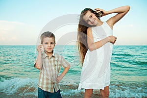 Sister and brother on the evening beach with the shells