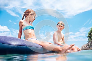 Sister and brother, have fun when swim on inflatable mattress in the sea. Careless childhood time photo