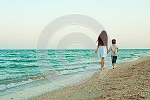 Sister and brother walking away by the evening beach.